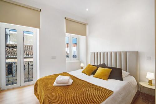 a white bedroom with a large bed with yellow pillows at Traditional 3 bedroom apartment in Alte