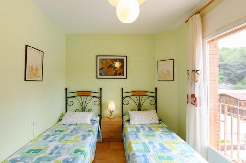two twin beds in a room with a window at Cal Vimon in Las Masucas