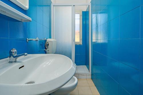 a blue bathroom with a sink and a toilet at I giardini di Cala D'ambra in San Teodoro