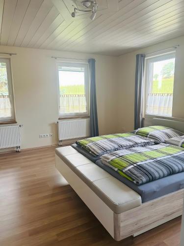 a bed in a room with two windows at Ferienwohnung Bauernpfad in Kressbronn am Bodensee