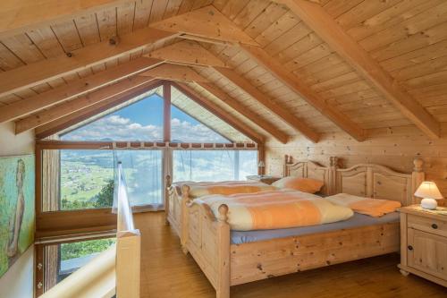 a bed in a room with a large window at Haus der Sinne Bregenzerwald in Tannen