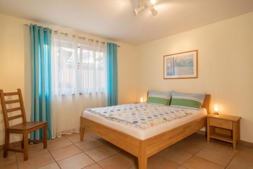 a bedroom with a bed and a chair and a window at Sabinas Gästewohnung in Wasserburg