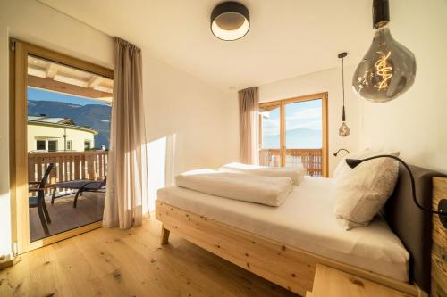 a bedroom with a bed with a view of a balcony at Apt Lärche - Nockerhof in Andrian