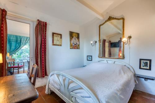 a bedroom with a bed with a mirror and a table at Le Mazet Du Maréchal Ferrant in Maguelonne-la-Sauvage