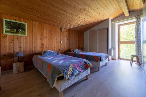 two beds in a room with wooden walls at Le Mas Saint Victor in Saint-Victor