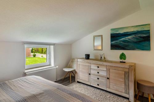 a bedroom with a bed and a dresser and a window at Krummes Häusschen an der Nordsee in Großheide
