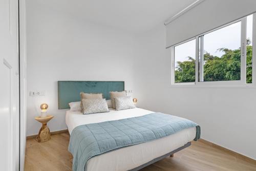 a white bedroom with a bed and two windows at Flamboyan 3 in Telde