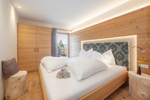 a bedroom with a bed with white pillows and a window at Furnerhof Apt Olpenglühn in Collepietra