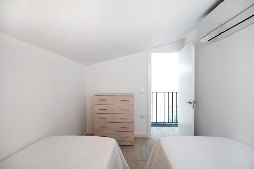 a white bedroom with two beds and a dresser at Alce piscina climatizada in Chiclana de la Frontera