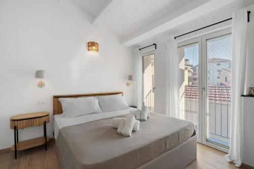 a white bedroom with a bed and a large window at Cinema Boutique Apartment Sestri in Sestri Levante