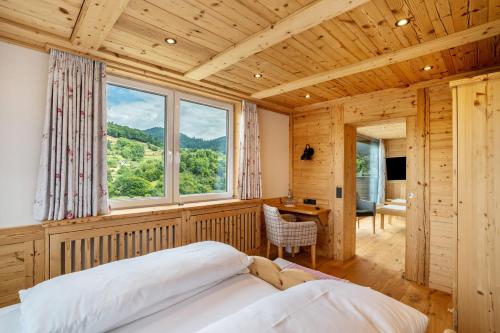 a bedroom with a bed and a large window at Wein- und Klimahotel Bergfriedel in Bühlertal