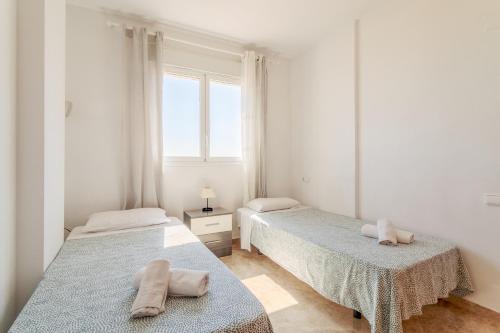 two beds in a white room with towels on them at El Mirador in Mutxamel