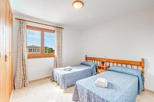 two beds in a room with a window at Apartamentos Karin 1ºb in Santanyi