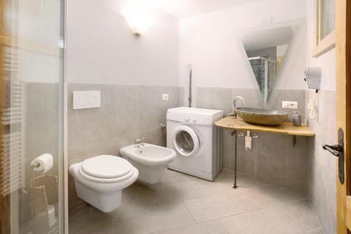 a bathroom with a toilet and a washing machine at Premesan 4 in Bormio
