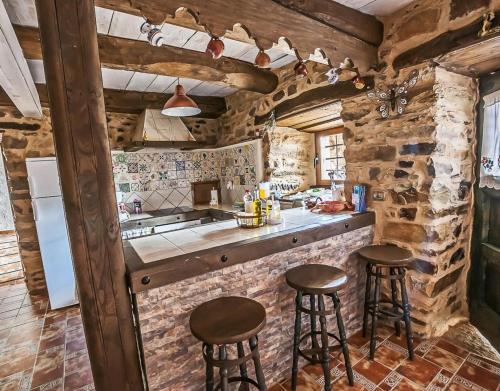a kitchen with stone walls and stools in a room at Jumaca in Valdespino de Somoza