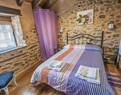 a bedroom with a bed and a stone wall at Jumaca in Valdespino de Somoza