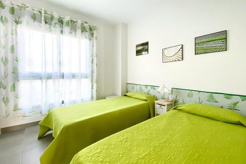 two lime green beds in a room with a window at Beach Apartment with Pool, Terrace in Taramay