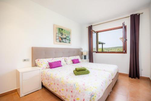 a bedroom with a bed with purple pillows and a window at Luxurious villa Sol de Mallorca in Sol de Mallorca