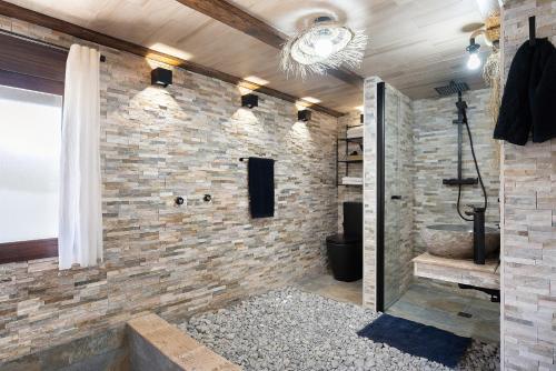 a bathroom with a stone wall and a shower at Loft Abanderao Piscina y Jacuzzi in Conil de la Frontera