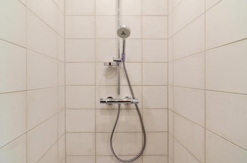 a shower with a shower head in a white tiled bathroom at Haus Schlossgarten in Hinte