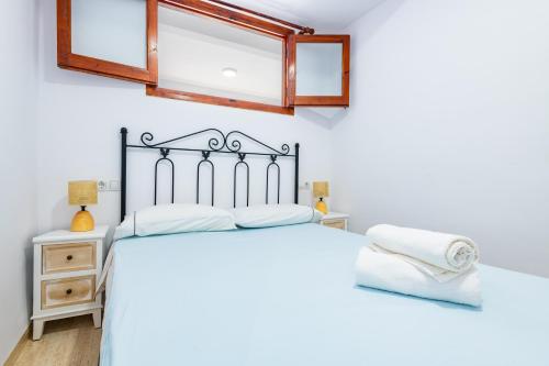 a bedroom with a bed with white sheets and a mirror at Los Arcos in Alcossebre