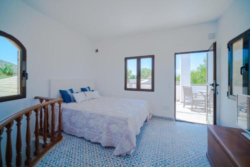 a white bedroom with a bed and a balcony at Sa vinya in Colonia de Sant Pere