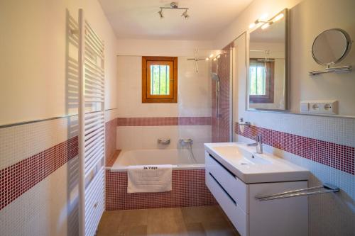 a bathroom with a tub and a sink and a mirror at Sa vinya in Colonia de Sant Pere