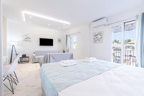 a white bedroom with two beds and a tv at Corfu Haven in Ágios Rókkos