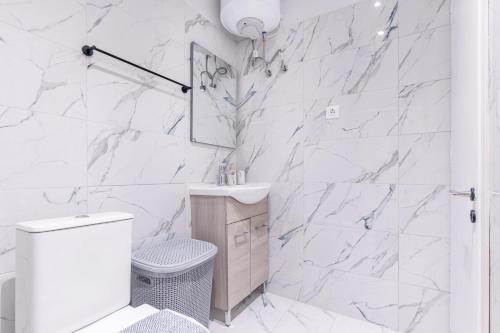 a white bathroom with a toilet and a sink at Corfu Haven in Ágios Rókkos