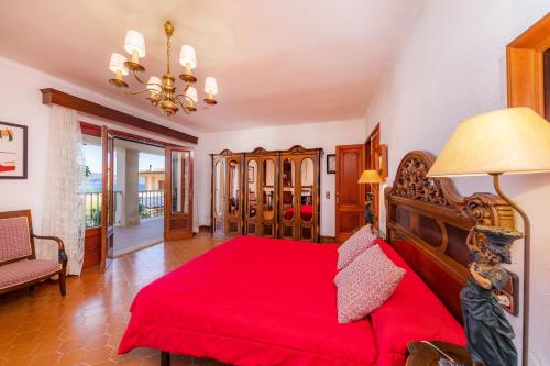 a bedroom with a red bed and a chandelier at Gran Vista Mar in Alcudia