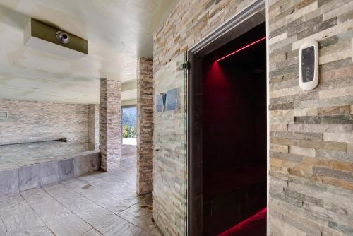a hallway with a brick wall and a red door at Relax and Happiness private Jacuzzi in Perledo