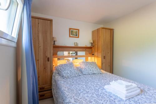 a bedroom with a bed with blue sheets and wooden cabinets at T3 Aramits Pyrénées Béarnaises in Aramits