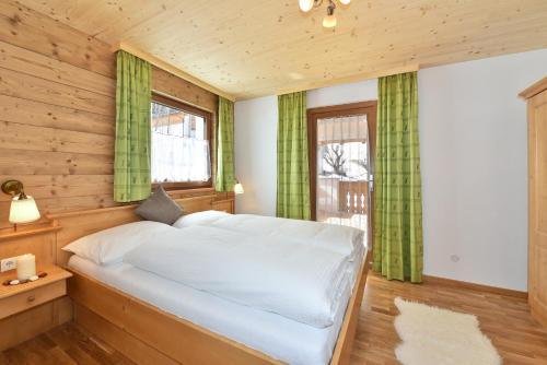 a bedroom with a large bed with green curtains at Joselehof App Arnika in Racines