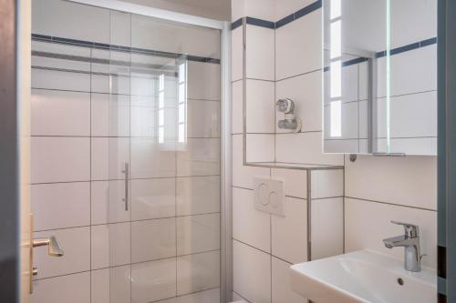 a white bathroom with a shower and a sink at Terrassenpark Apartment 160 in Schonach