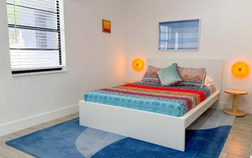 a white bedroom with a bed with a blue rug at After Hours - Wilton Drive and Jacuzzi in Fort Lauderdale