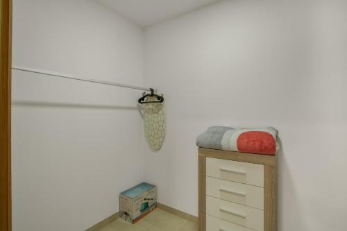 a room with a white wall with a bed and a drawer at Edificio Bentejui 1 in Las Palmas de Gran Canaria