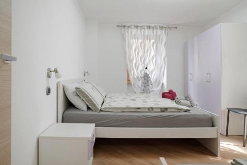 a white bedroom with a bed with a window at Casa Picchio in Rabbi
