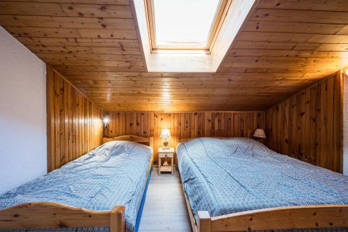 two beds in a wooden room with a window at L'esterelle in La Plagne Tarentaise