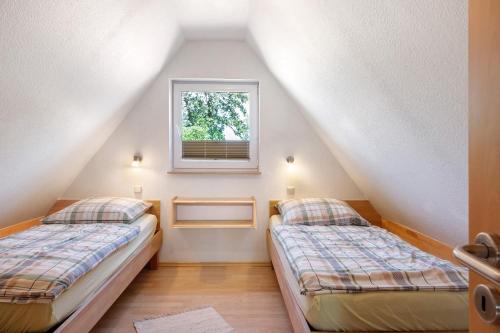 two beds in a attic bedroom with a window at Haus Schöneck in Otterndorf