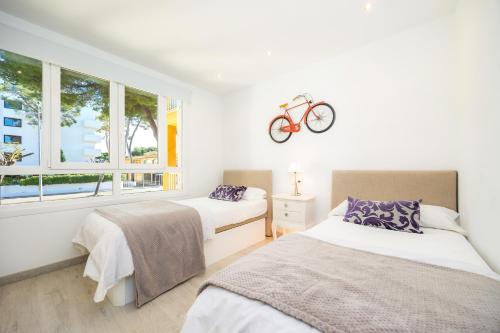 a bedroom with two beds and a bike on the wall at Lagomar in Alcudia