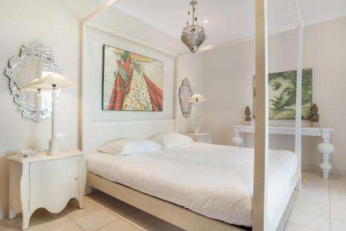 a white bedroom with a canopy bed and paintings at Luxury Villa Arcos Golf in Arcos de la Frontera