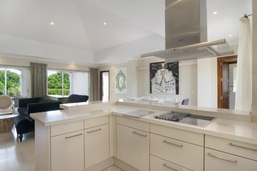 a kitchen with white cabinets and a living room at Luxury Villa Arcos Golf in Arcos de la Frontera
