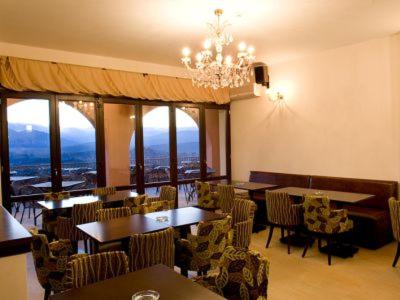 a dining room with tables and chairs and a chandelier at Vytina Mountain View Hotel in Vytina