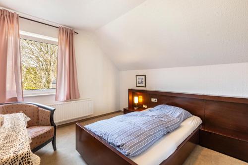 a bedroom with a bed and a chair and a window at Ferienwohnung Grothoff in Olsberg