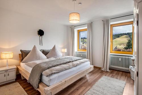 a bedroom with a large bed and two windows at Haus Bergruh Kuckucksnest in Todtnauberg