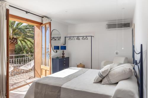 a white bedroom with a bed and a balcony at Sembat de Mar in Cala Millor