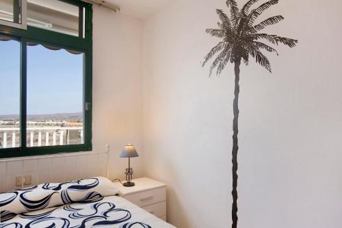 a bedroom with a palm tree on the wall at Balcón de Amadores - Beach view in Puerto Rico de Gran Canaria