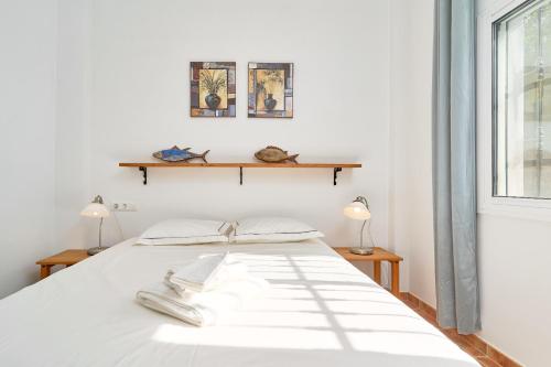 a white bed with two lamps and a window at Villa Amapola in Caserío Carraspite