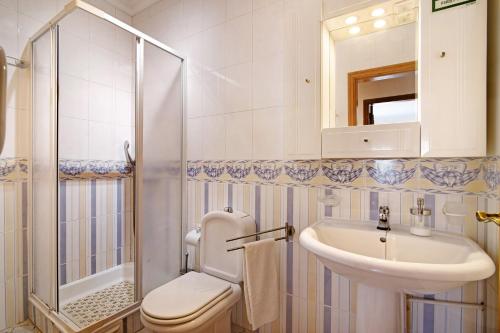 a bathroom with a toilet and a sink and a shower at Columbus Beach Apartment in Quarteira