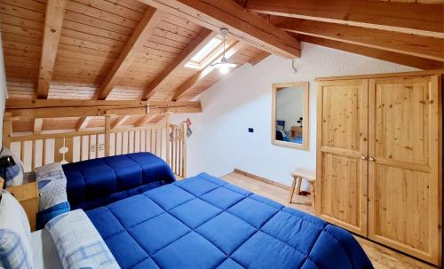 a bedroom with a blue bed and wooden ceilings at Appartamento Adamello 13 in Pinzolo